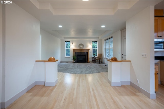 unfurnished living room with a tray ceiling and light hardwood / wood-style flooring