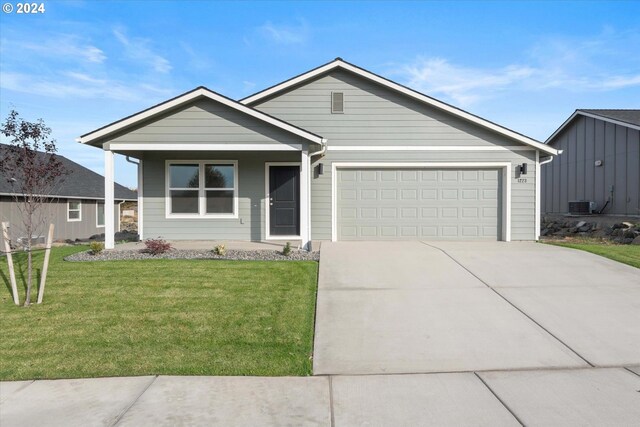 ranch-style house with central AC unit, a front yard, and a garage