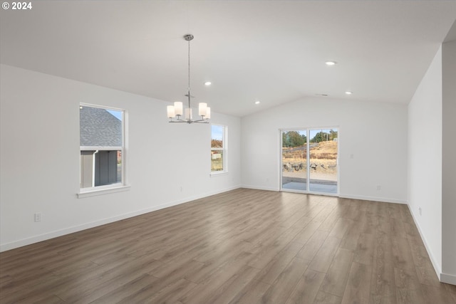 unfurnished room featuring an inviting chandelier, hardwood / wood-style flooring, and vaulted ceiling