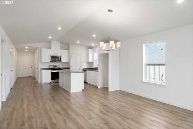 kitchen with light wood-type flooring, vaulted ceiling, stainless steel appliances, hanging light fixtures, and white cabinets