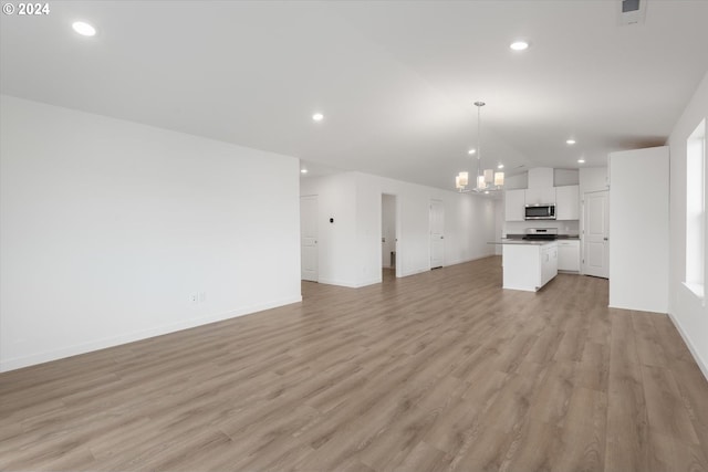 unfurnished living room with an inviting chandelier, lofted ceiling, and light hardwood / wood-style floors