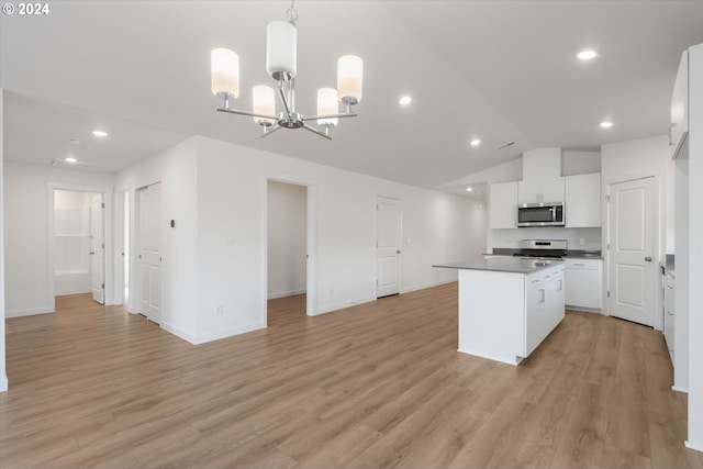 kitchen with hanging light fixtures, vaulted ceiling, white cabinetry, light hardwood / wood-style flooring, and appliances with stainless steel finishes