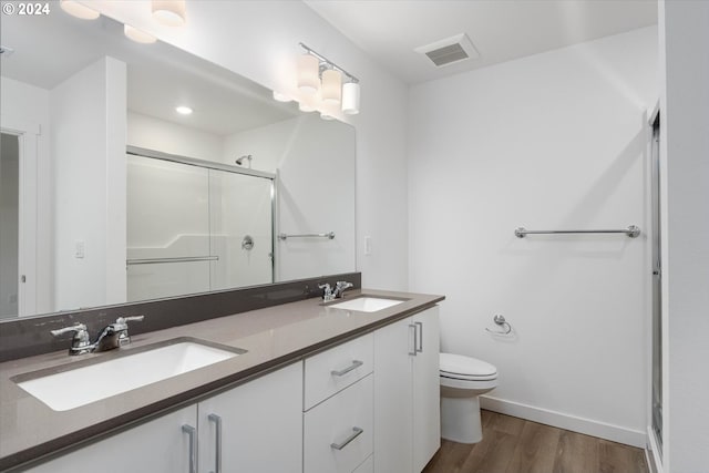 bathroom featuring hardwood / wood-style floors, vanity, toilet, and a shower with shower door