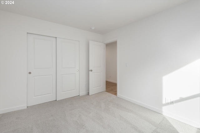 unfurnished bedroom featuring light colored carpet and a closet