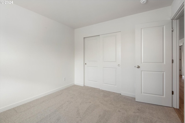 unfurnished bedroom featuring a closet and light colored carpet