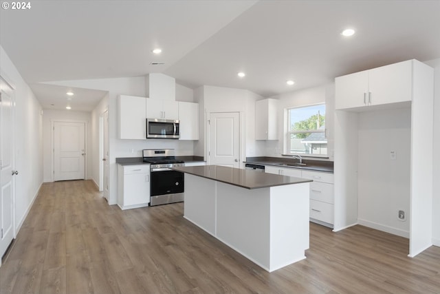 kitchen featuring appliances with stainless steel finishes, a kitchen island, vaulted ceiling, and white cabinets