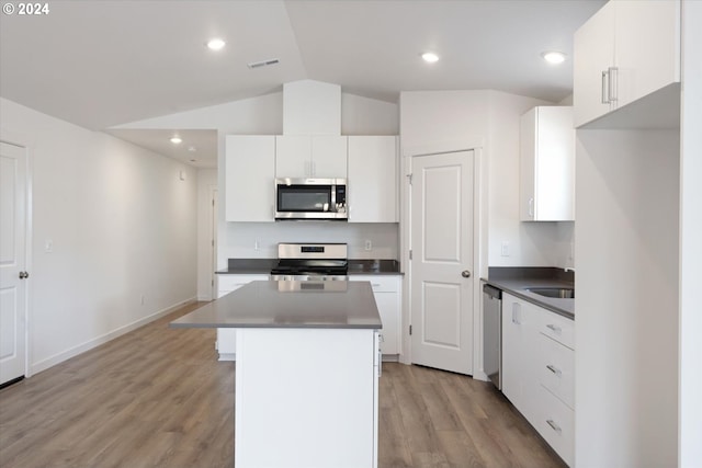 kitchen with light hardwood / wood-style flooring, stainless steel appliances, vaulted ceiling, and white cabinetry