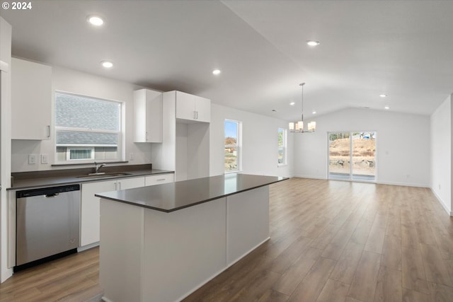 kitchen featuring a kitchen island, light hardwood / wood-style flooring, vaulted ceiling, white cabinets, and stainless steel dishwasher