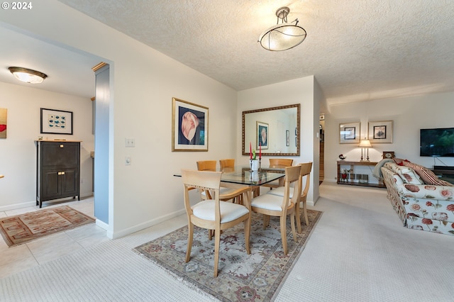 dining area featuring light carpet and a textured ceiling