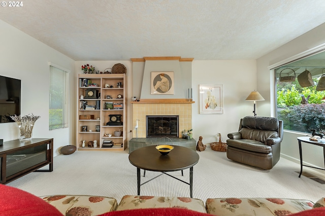 carpeted living room with a tile fireplace and a textured ceiling