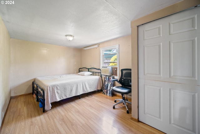 bedroom featuring a textured ceiling, light wood-type flooring, and cooling unit