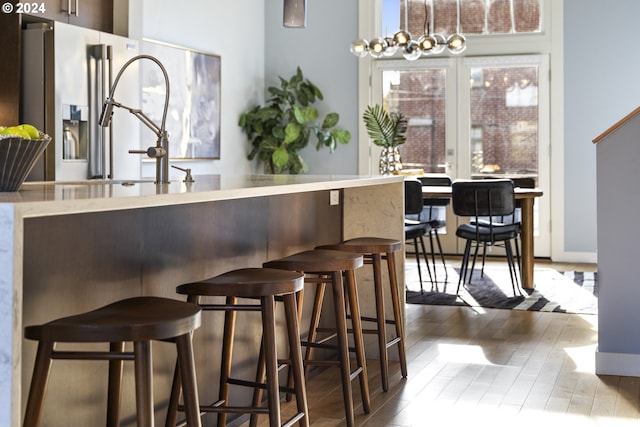 bar featuring hardwood / wood-style flooring and stainless steel refrigerator with ice dispenser