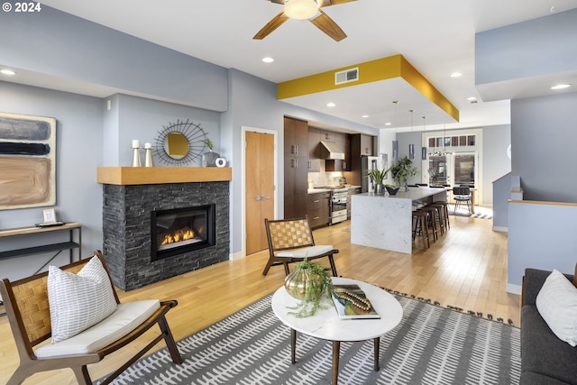 living room with light hardwood / wood-style floors, ceiling fan, and a fireplace