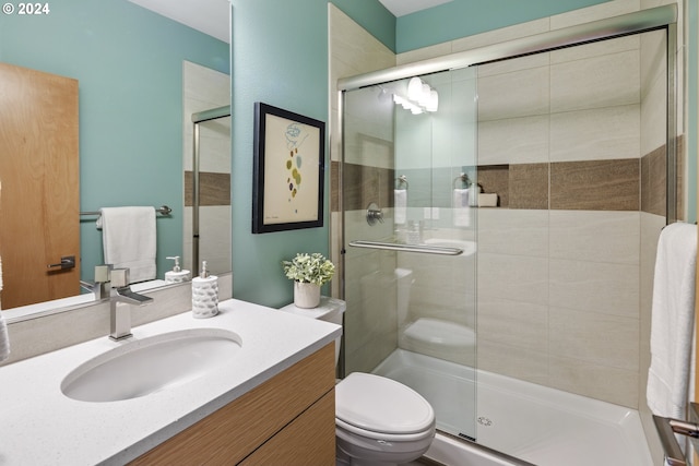 bathroom with toilet, a shower with shower door, and vanity