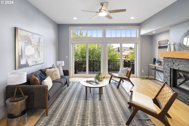 living room with wood-type flooring, a fireplace, and ceiling fan