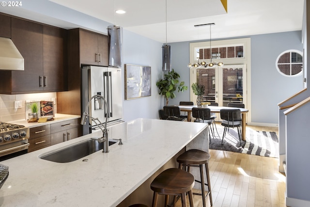 kitchen with light stone counters, high end appliances, light hardwood / wood-style floors, and sink