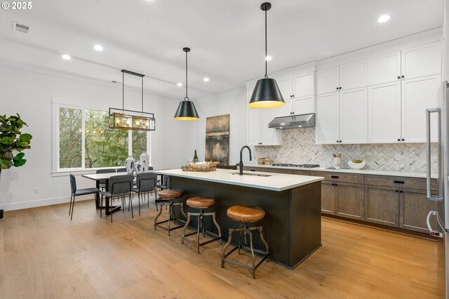 kitchen featuring white cabinets, sink, pendant lighting, and a kitchen island with sink