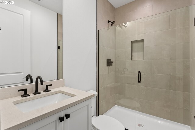 bathroom featuring vanity, a shower with shower door, and toilet