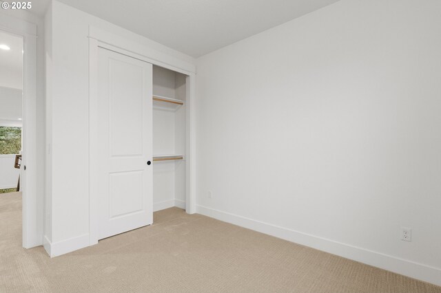 unfurnished bedroom featuring light colored carpet and a closet