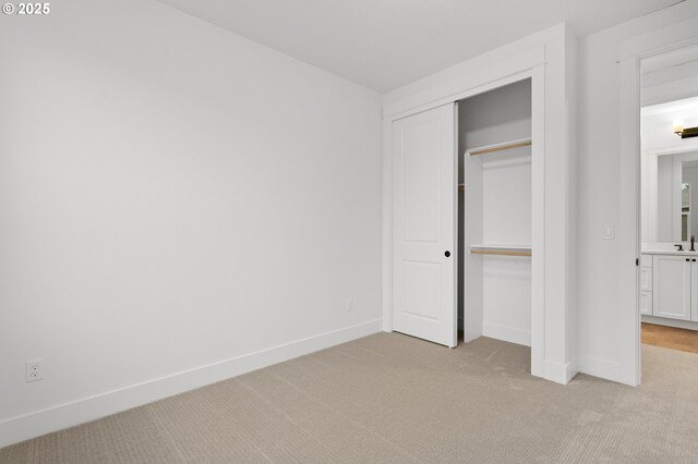 unfurnished bedroom featuring light colored carpet and a closet