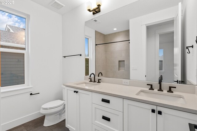 bathroom featuring vanity, a wealth of natural light, tile patterned floors, and toilet