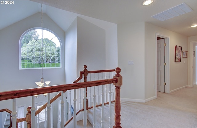 corridor featuring light colored carpet, an inviting chandelier, and lofted ceiling