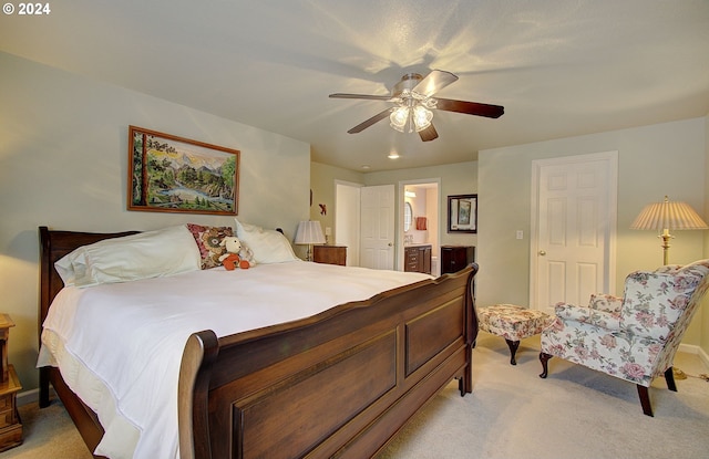 bedroom with connected bathroom, light colored carpet, and ceiling fan