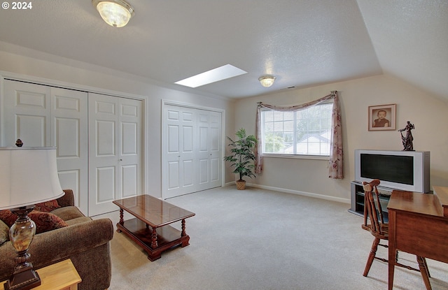 living room with lofted ceiling with skylight, light colored carpet, and a textured ceiling