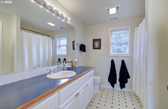 bathroom featuring vanity, a healthy amount of sunlight, and toilet