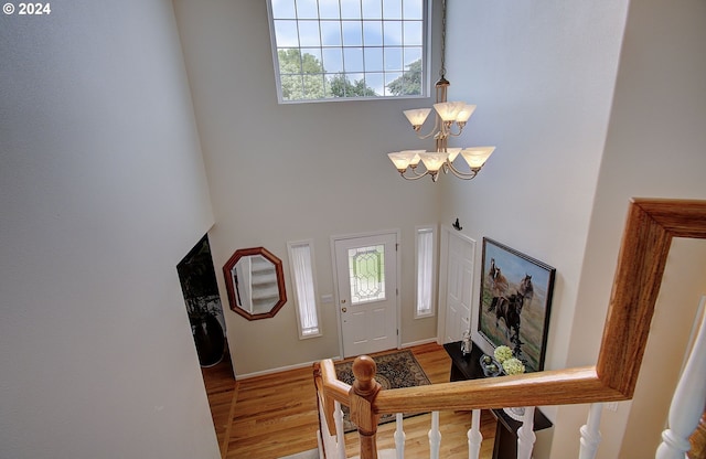 foyer entrance with plenty of natural light, wood-type flooring, and a notable chandelier