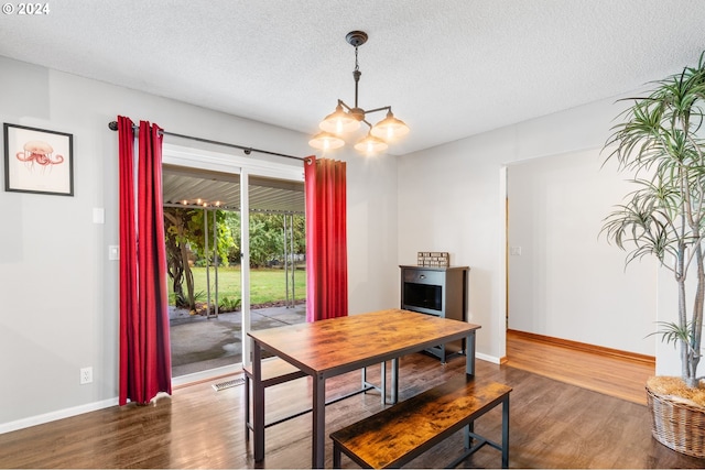 dining area with hardwood / wood-style floors, a textured ceiling, and an inviting chandelier