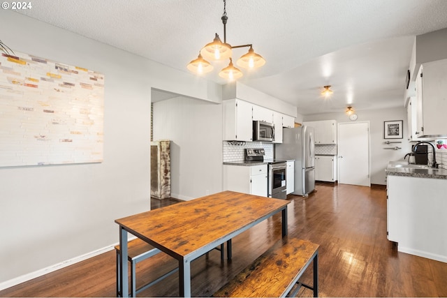 dining space featuring an inviting chandelier, a textured ceiling, sink, and dark hardwood / wood-style flooring