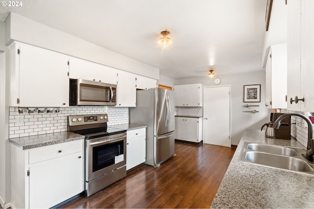 kitchen with appliances with stainless steel finishes, sink, backsplash, white cabinetry, and dark wood-type flooring