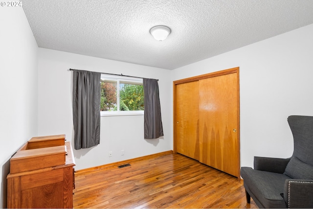 sitting room featuring light hardwood / wood-style flooring and a textured ceiling