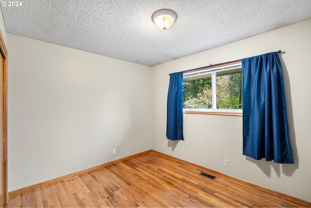 empty room with a textured ceiling and hardwood / wood-style flooring