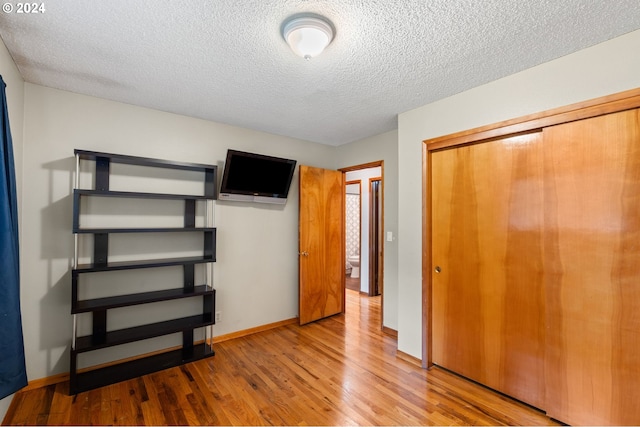 unfurnished bedroom with a closet, hardwood / wood-style floors, and a textured ceiling