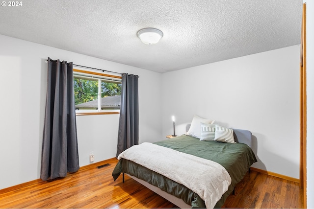 bedroom featuring a textured ceiling and hardwood / wood-style flooring