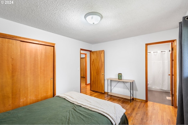 bedroom with a closet, a textured ceiling, ensuite bathroom, and wood-type flooring