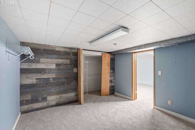 basement featuring wood walls and carpet