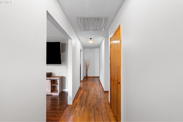 hallway with a textured ceiling and dark hardwood / wood-style flooring