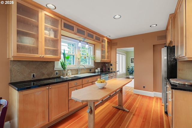 kitchen with light wood finished floors, backsplash, baseboards, and a sink