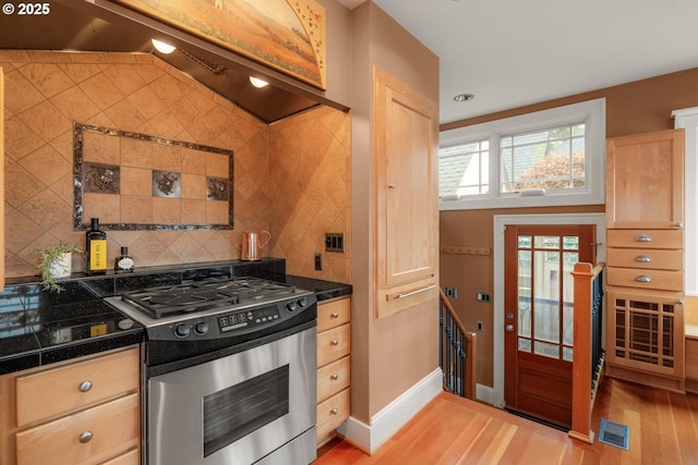 2130 NE Klickitat St, Portland, OR 97212 - kitchen with stainless steel gas stove, light wood-style flooring, custom exhaust hood, backsplash, and tile counters