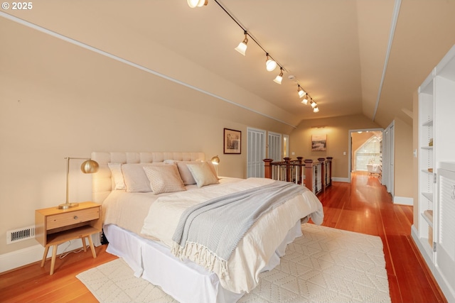 bedroom featuring vaulted ceiling, wood finished floors, visible vents, and baseboards