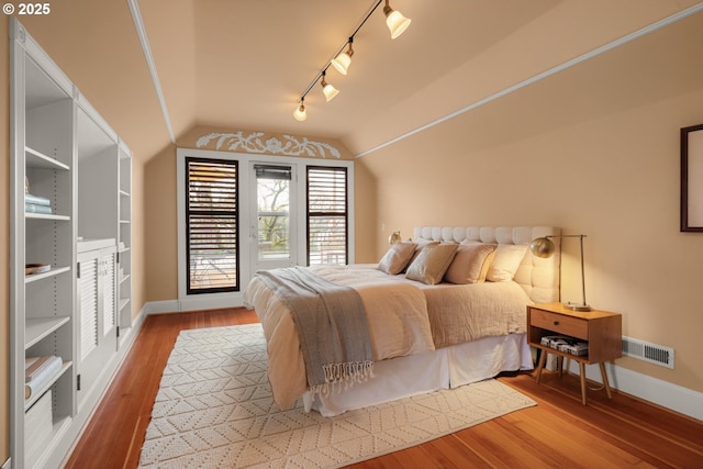 2130 NE Klickitat St, Portland, OR 97212 - bedroom with rail lighting, baseboards, lofted ceiling, and wood finished floors