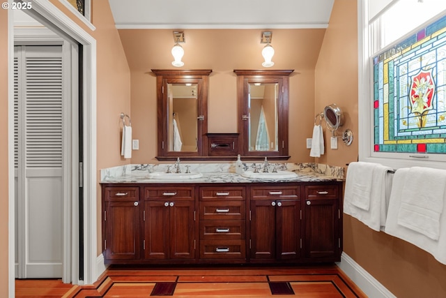 bathroom featuring double vanity, wood finished floors, baseboards, and a sink