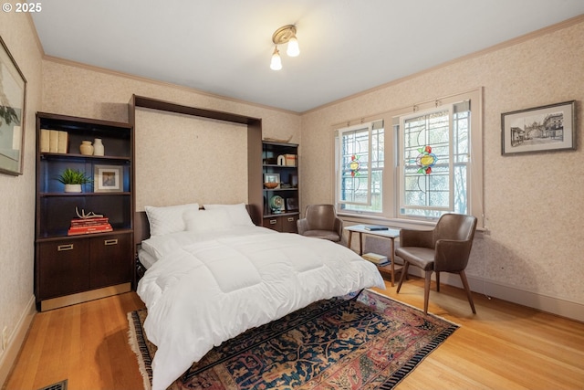 bedroom featuring wallpapered walls, wood finished floors, and ornamental molding