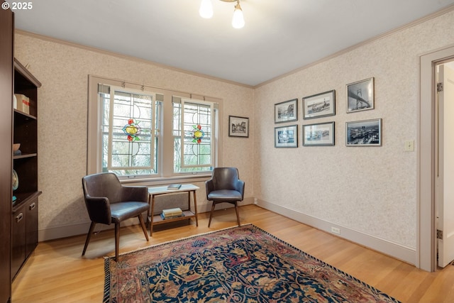 sitting room with light wood-style flooring, wallpapered walls, baseboards, and ornamental molding