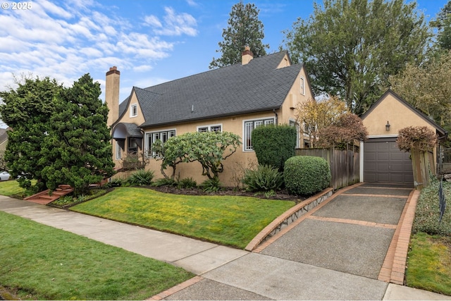 view of front facade featuring stucco siding, an outdoor structure, a front yard, and fence