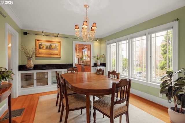 dining room featuring an inviting chandelier, light wood-style flooring, a healthy amount of sunlight, and visible vents