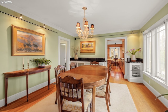 dining space with light wood-type flooring, plenty of natural light, and an inviting chandelier